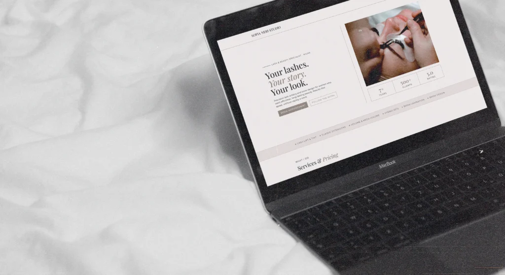 An affordable one-page website design for a beauty studio shown on a laptop screen over white bedding.