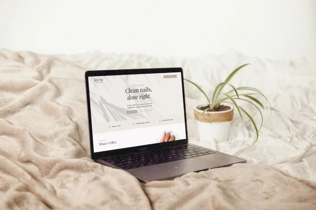 Layout minimale di un sito web one-page economico per un centro estetico unghie mostrato su un laptop con pianta e coperta beige sullo sfondo.
