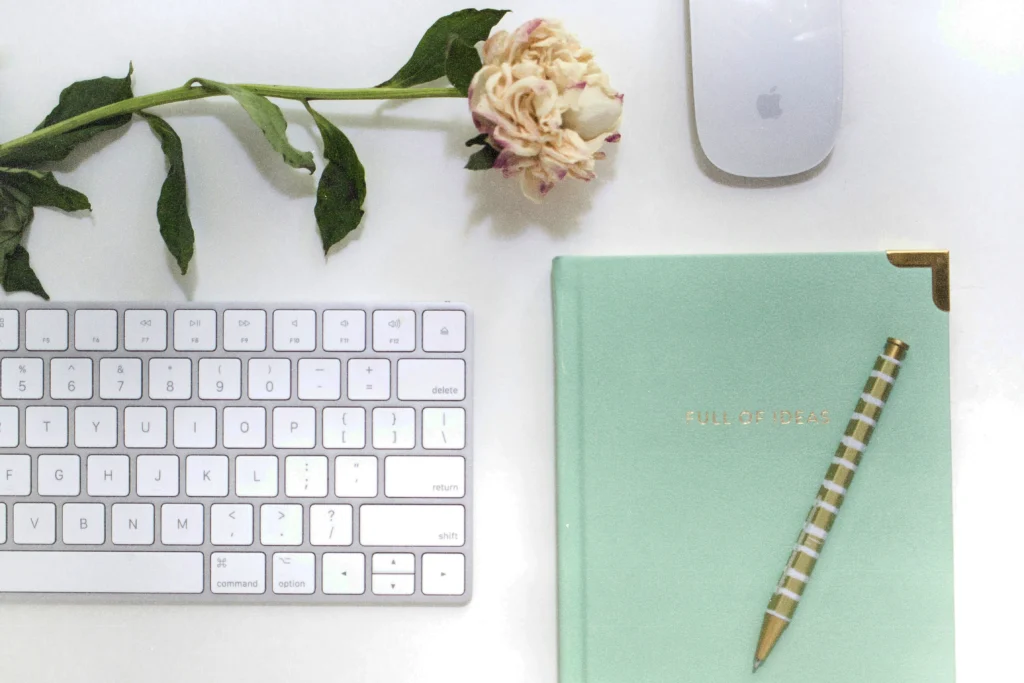 Website launch checklist: notebook with gold pen on a minimal desk with dried flower and keyboard